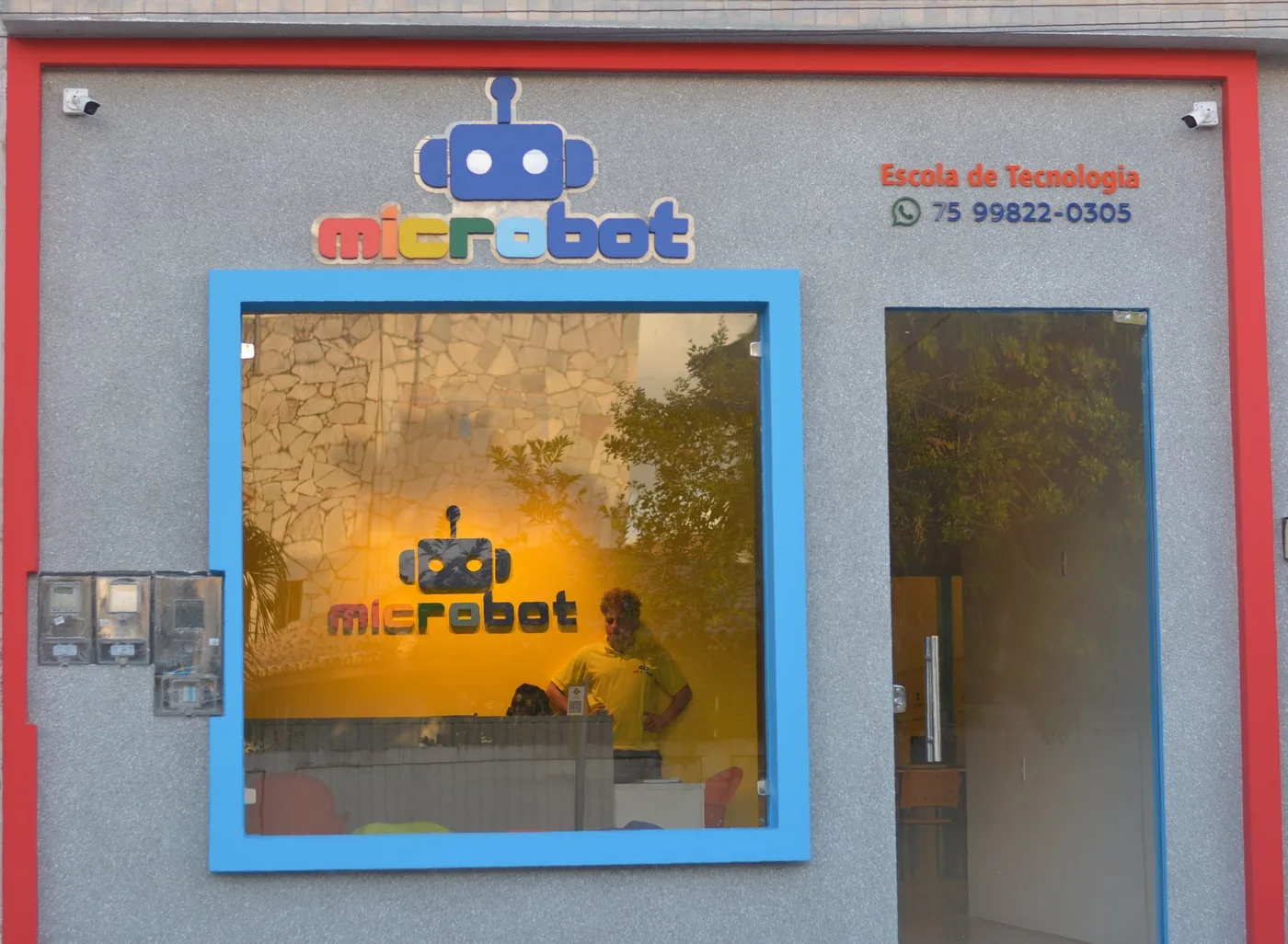 Fachada real da Microbot com a marca oficial e a entrada da escola