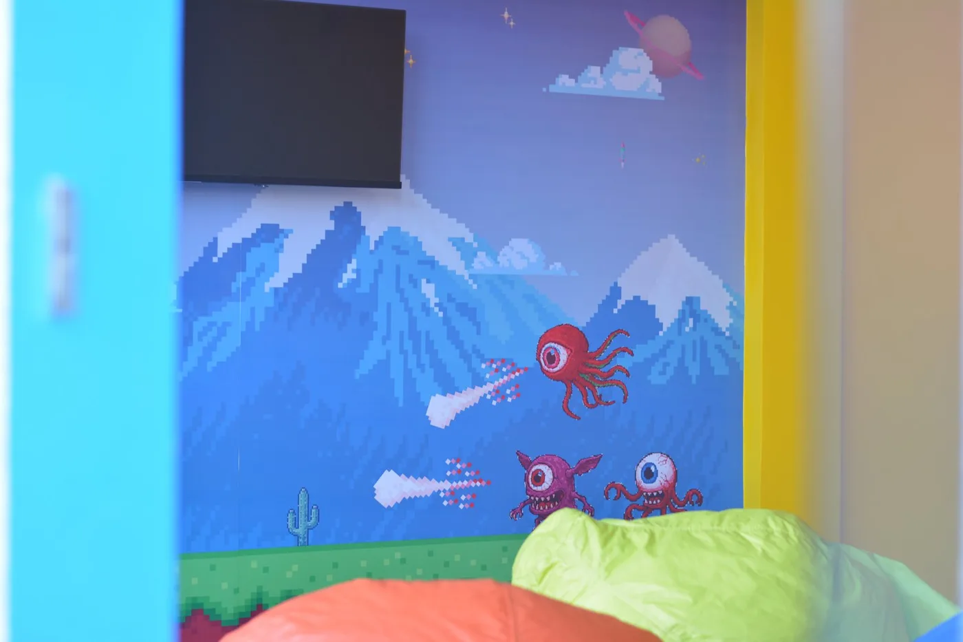 Espaço da escola com desenhos de montanhas na parede e pufes